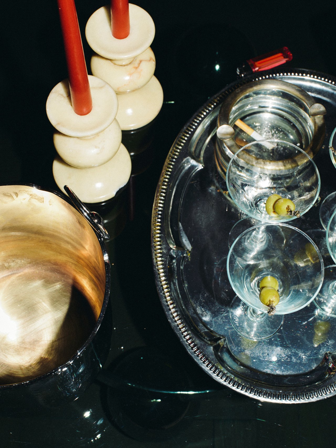 Coupe glasses with olives on a silver tray beside candle holders at Better Days